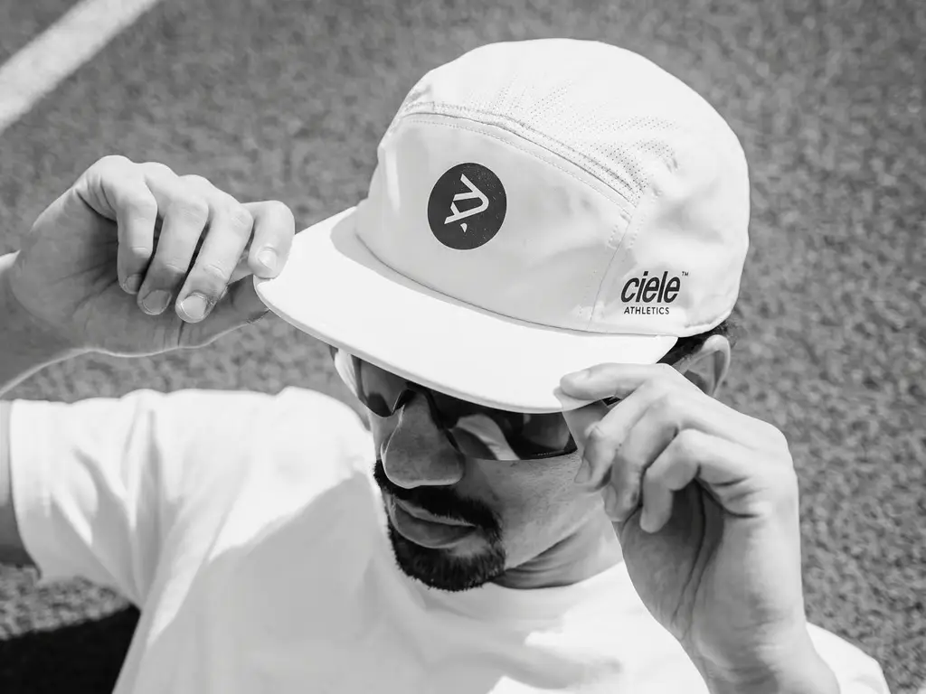 Casquette de course Sexy Pace Collective blanche, portée avec lunettes de soleil