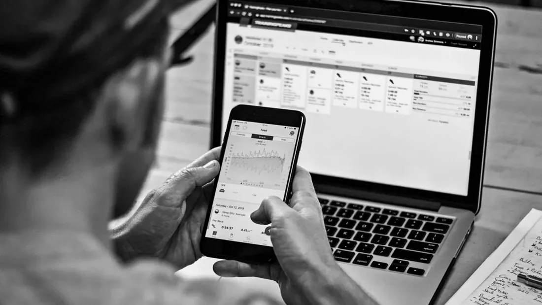 Coach qui consulte les données d'entraînement sur téléphone et ordinateur